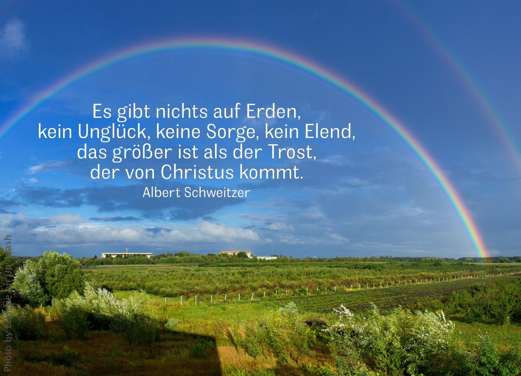 Großer Regenbogen spannt sich weit über grünem Land