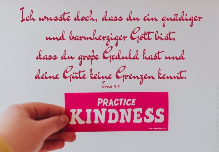 Hand hält Schild: Practice Kindness