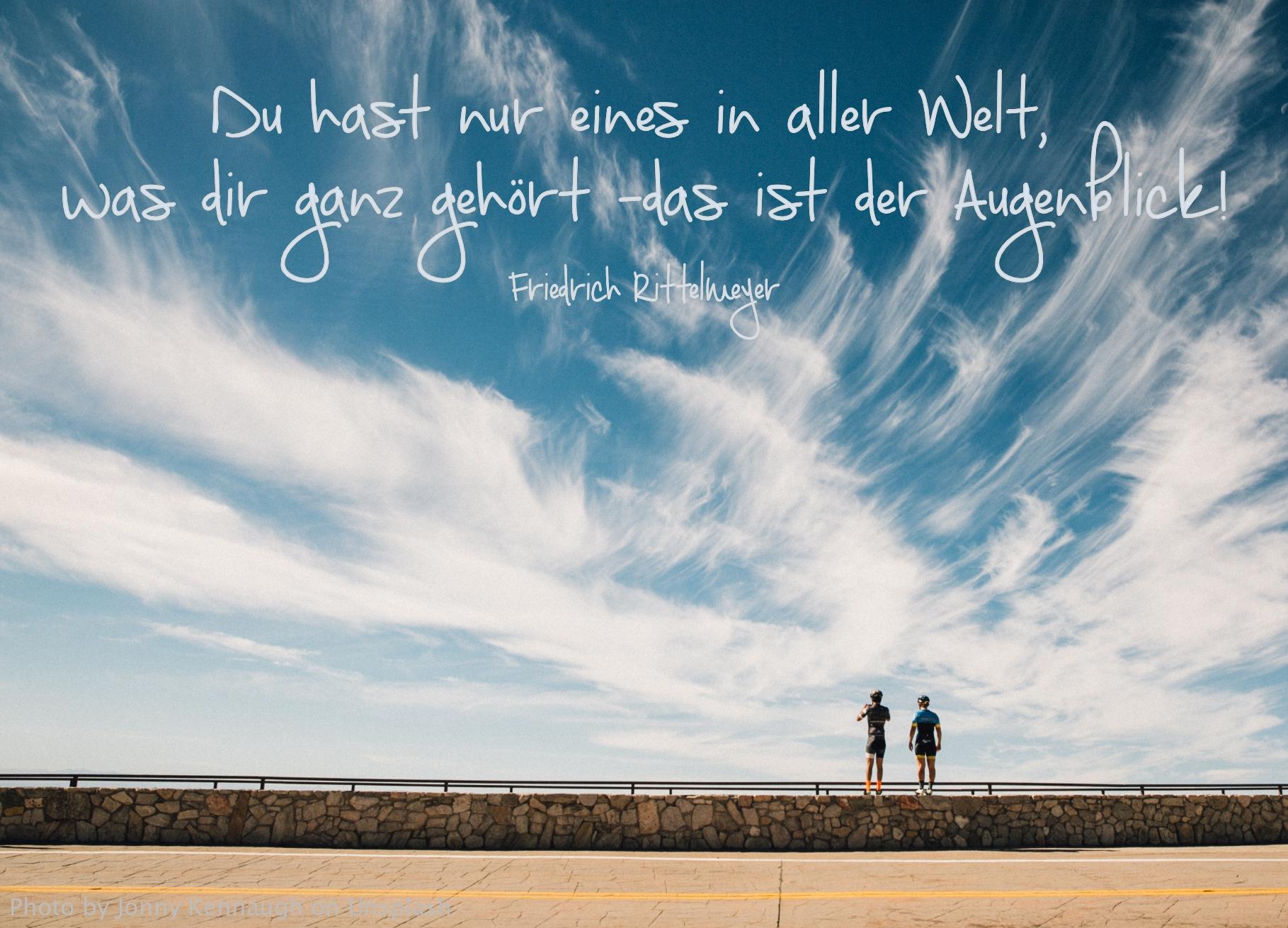 zwei Personen auf Steinmauer unter blauem wolkigen Himmel