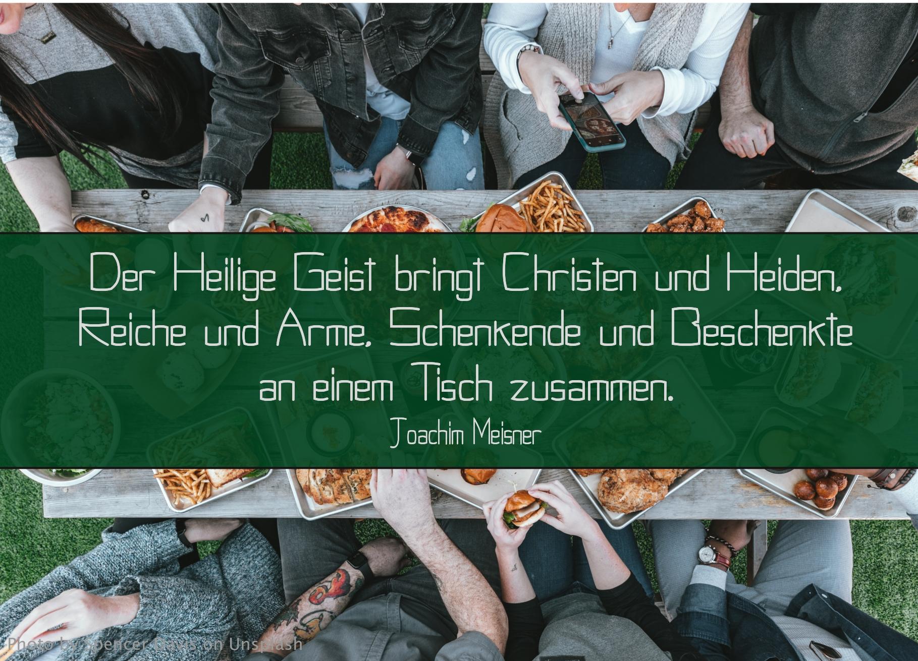 acht Personen sitzen an einem Tisch mit Essen